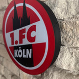 „Beleuchteter Fanartikel des 1. FC Köln in kräftigem Rot und Weiß.“
